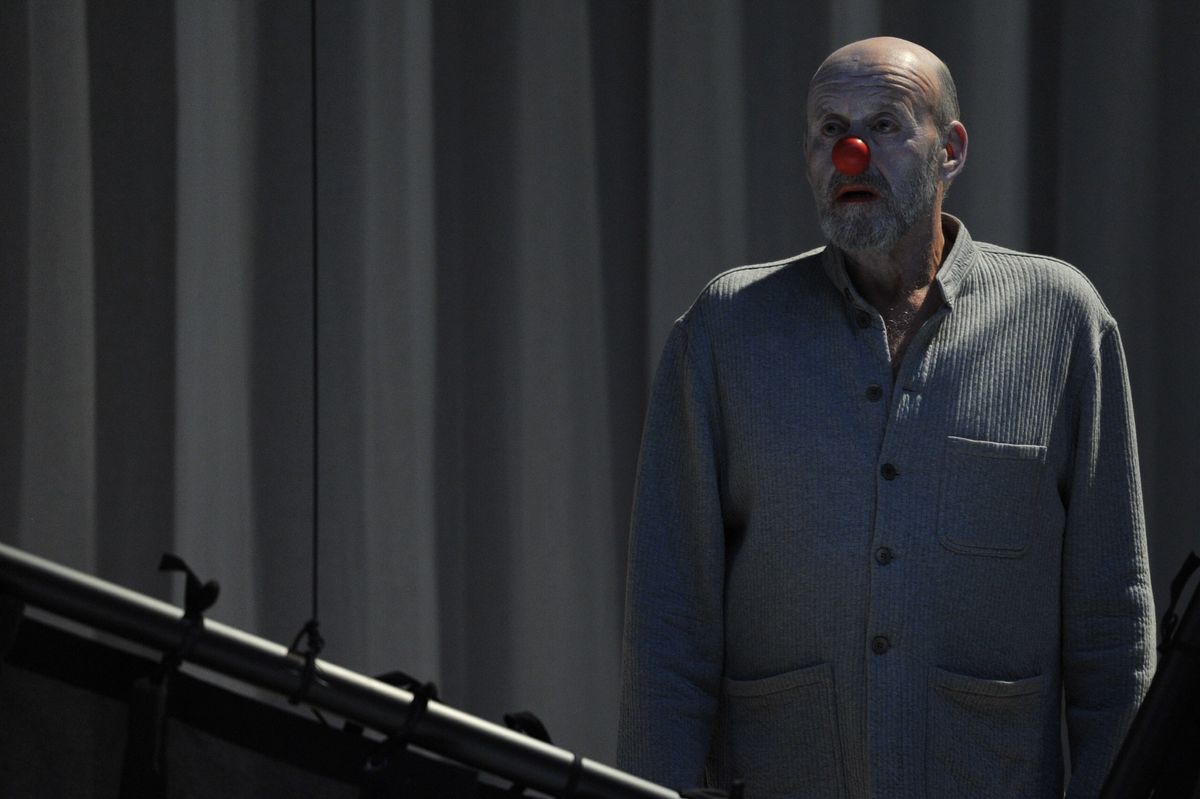 un comédien avec un nez de clown et le visage blanc